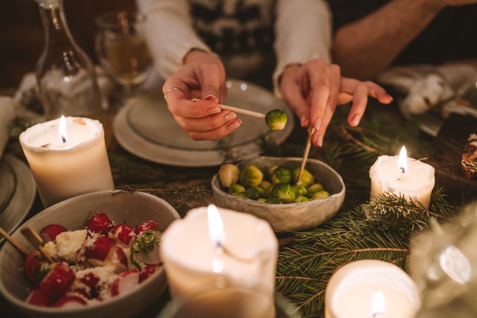 Candlelit Christmas table with Brussels sprouts, roasted vegetables and fir branches