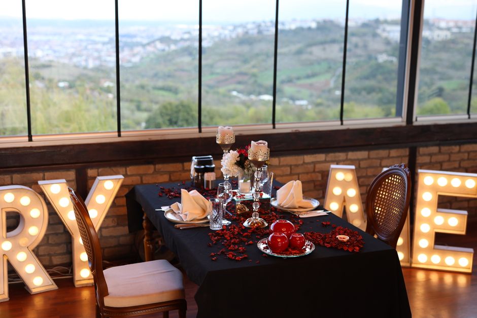 Candlelit dinner table for two with roses and napkins by a window