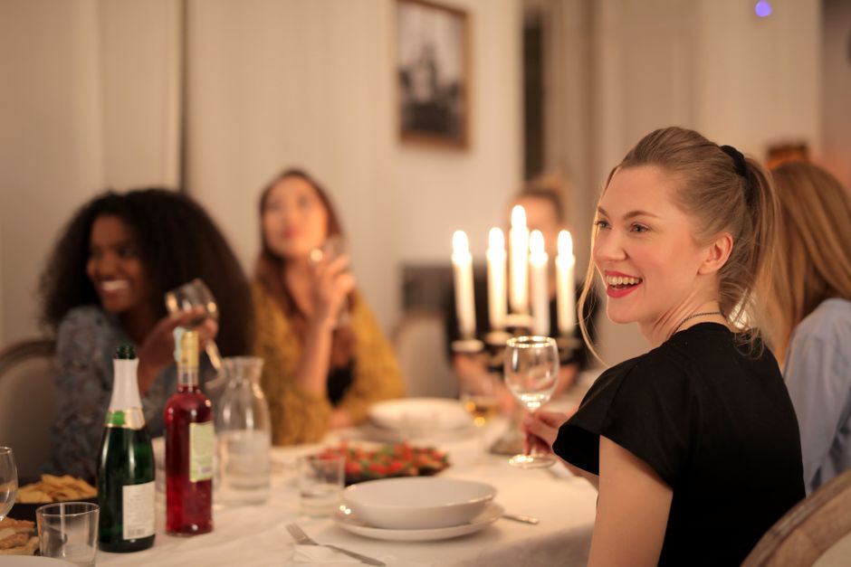 Friends laughing around a candlelit dinner party table