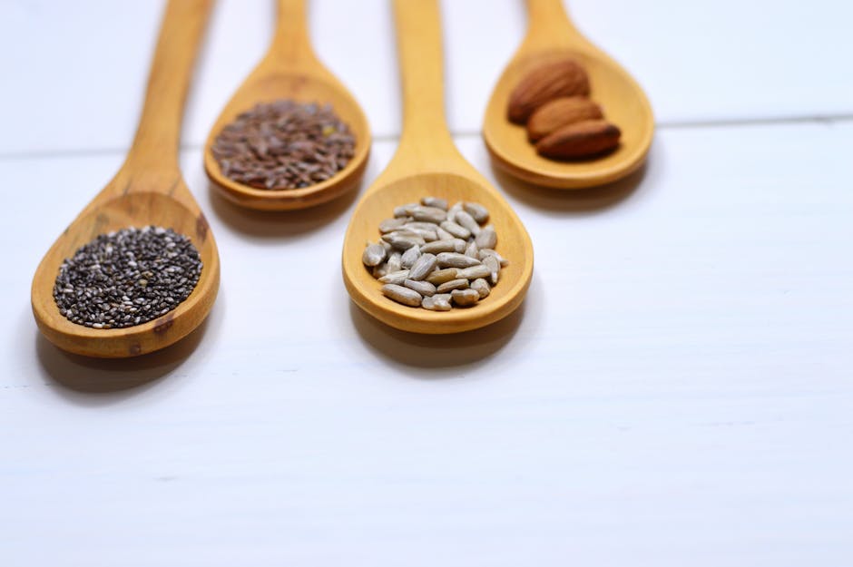 Bottle of algae oil omega-3 capsules next to flaxseed, chia, walnuts, and hemp seeds