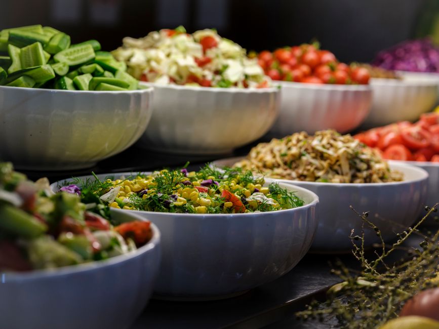 Bowls of salads and vegetable dishes lined up on a buffet table